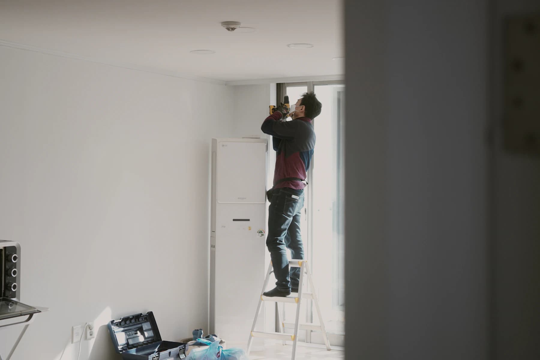 Techniker auf einer Leiter prüft die Decke in einem leeren Raum