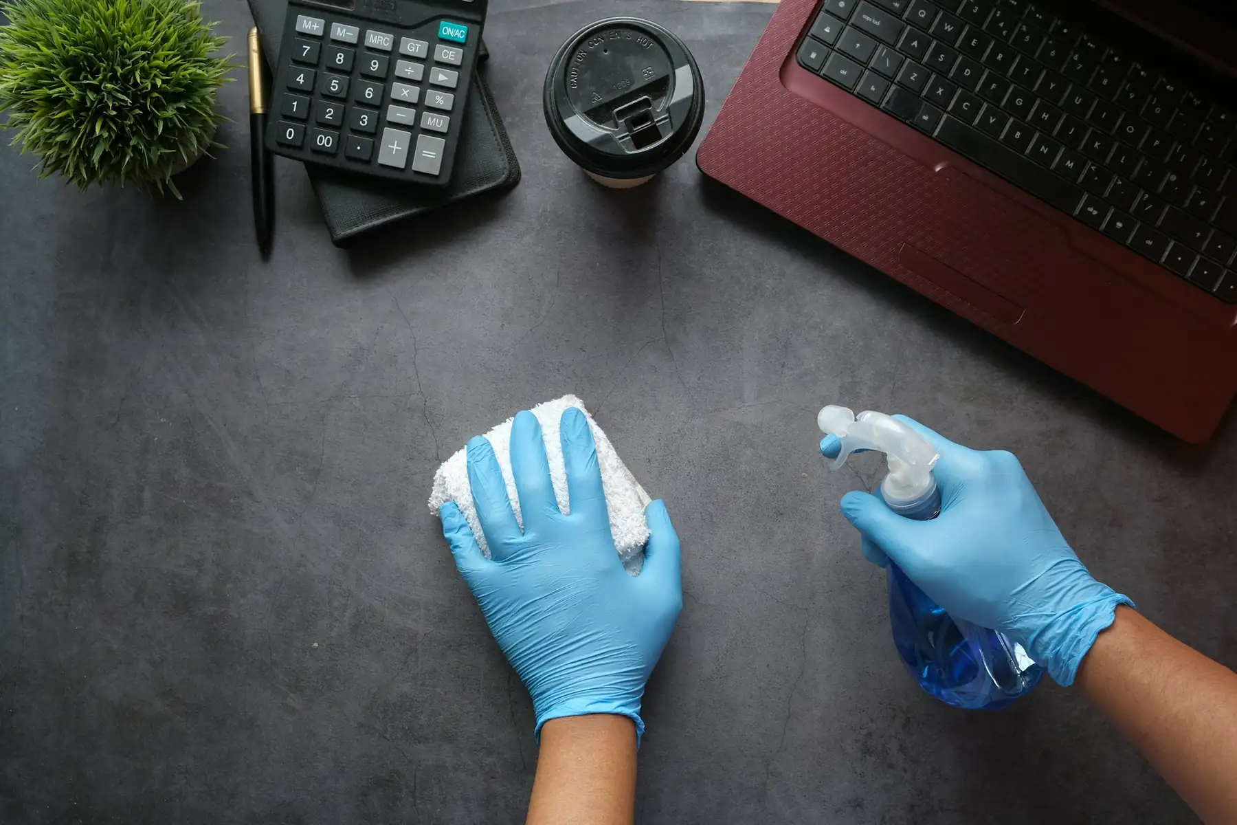 Hände in Handschuhen reinigen einen Schreibtisch